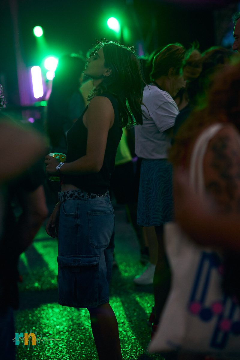 Festivalgoer in the crowd under green lights at Canela Party 2026