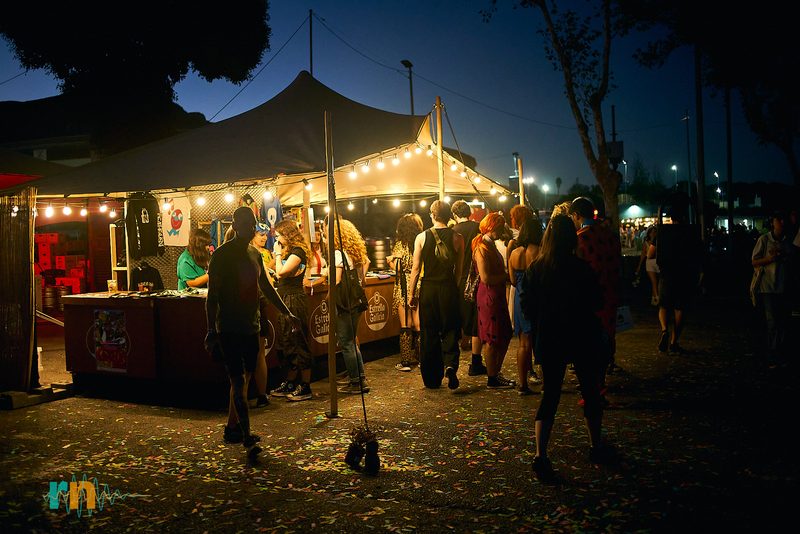 Festivalgoers in the lit food and drink area at night