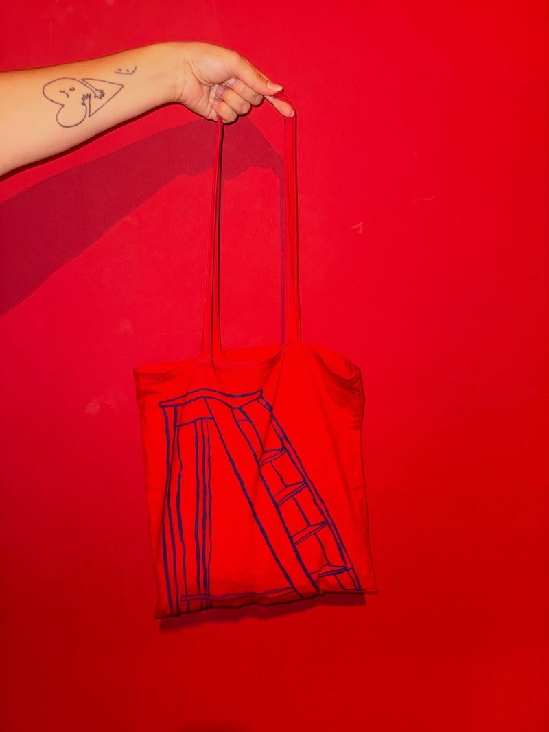 Red Construimos Escaleras merchandise tote bag featuring a staircase motif