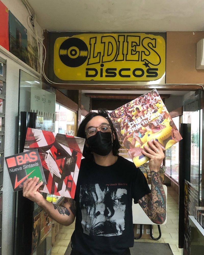 Person showing records in front of Oldies Discos sign