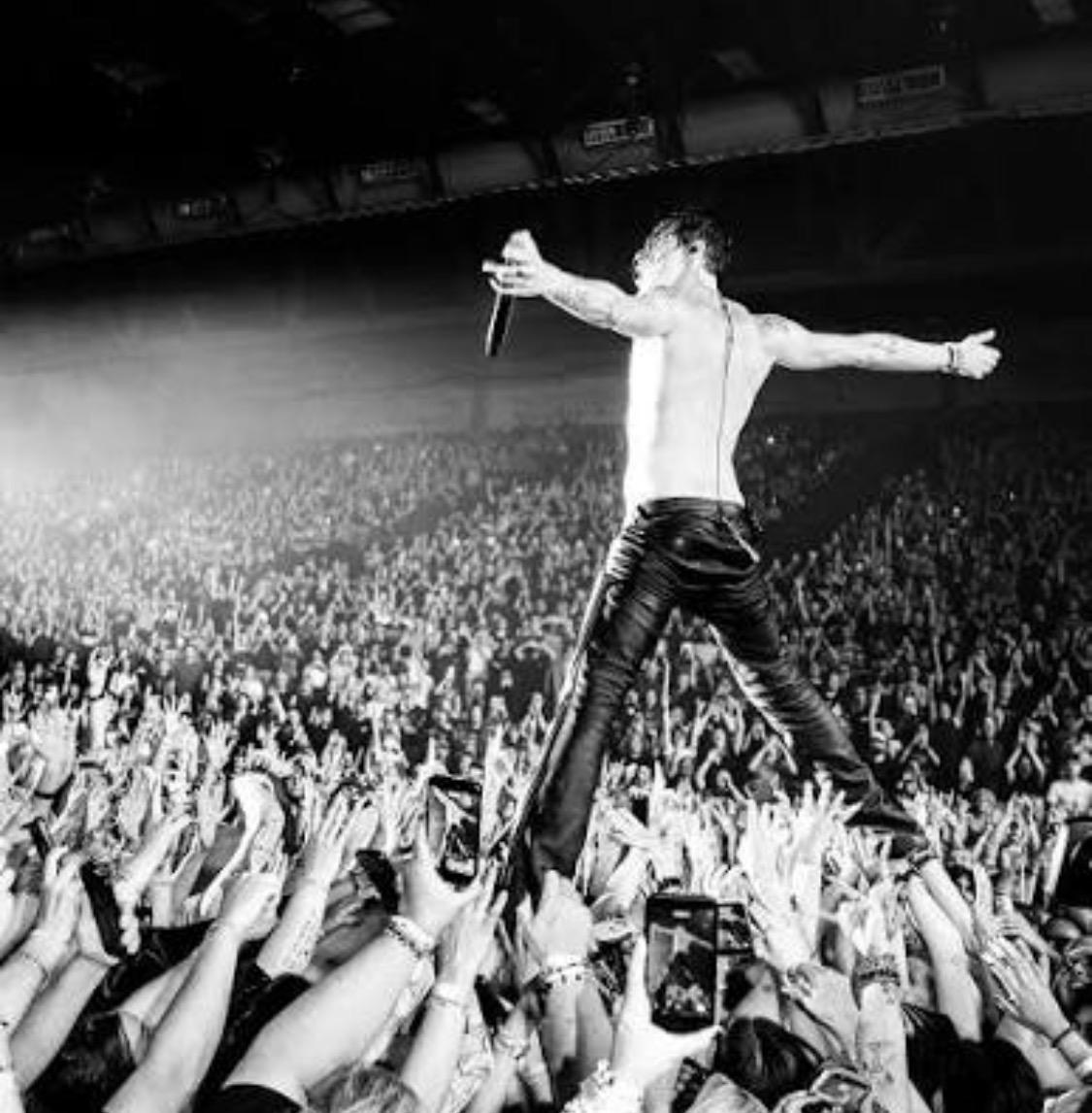 Vocalista de rock sobre el p&uacute;blico en un concierto multitudinario.