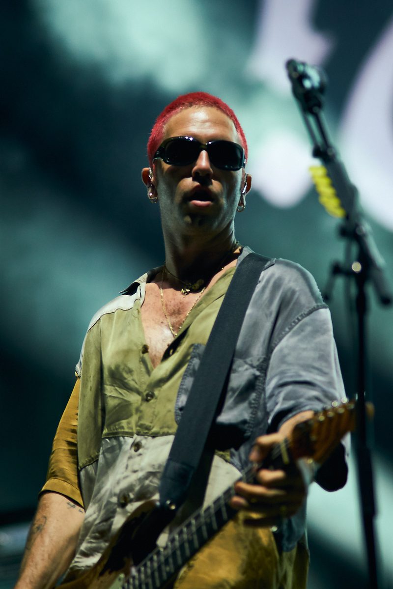 A Fontaines D.C. guitarist plays in sunglasses under green light in Alicante, Spain.