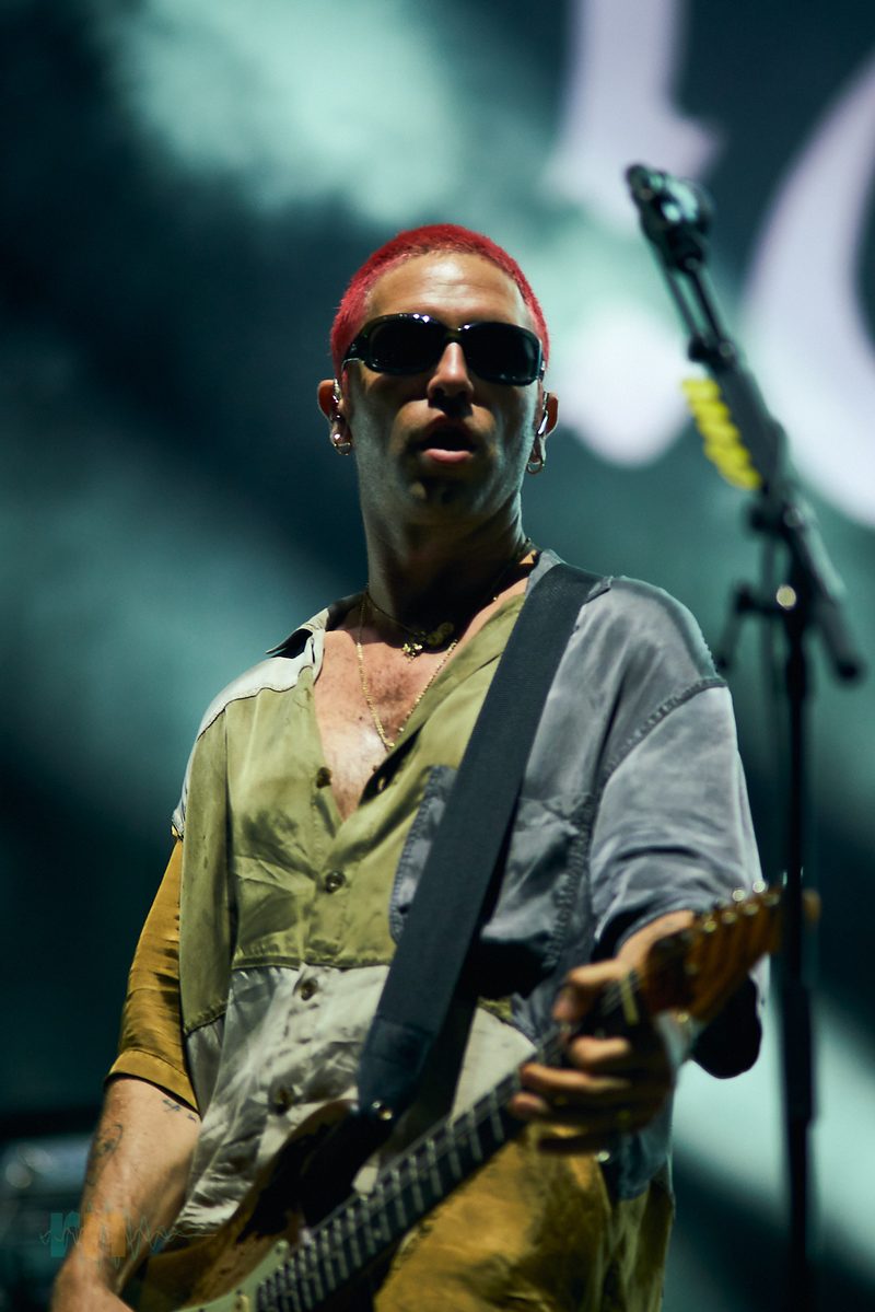 A Fontaines D.C. guitarist plays in sunglasses under green light in Alicante, Spain.