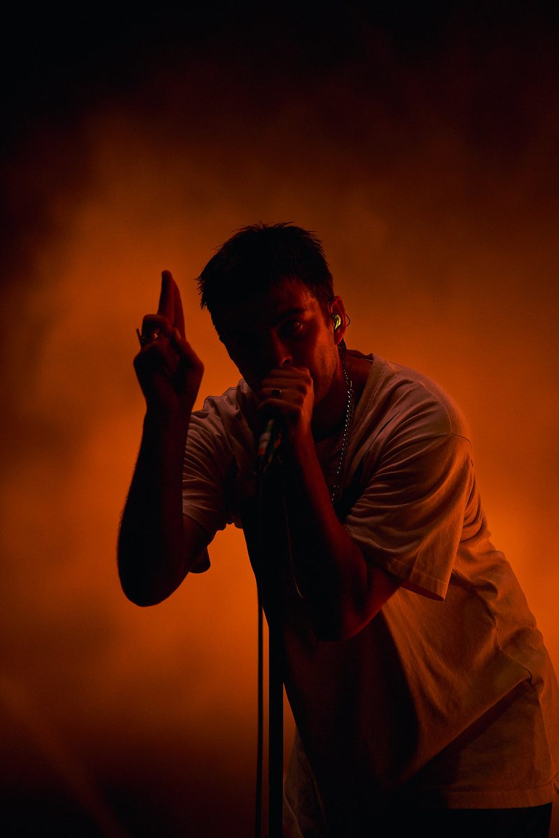 The Fontaines D.C. singer points upwards while performing under orange light in Alicante, Spain.
