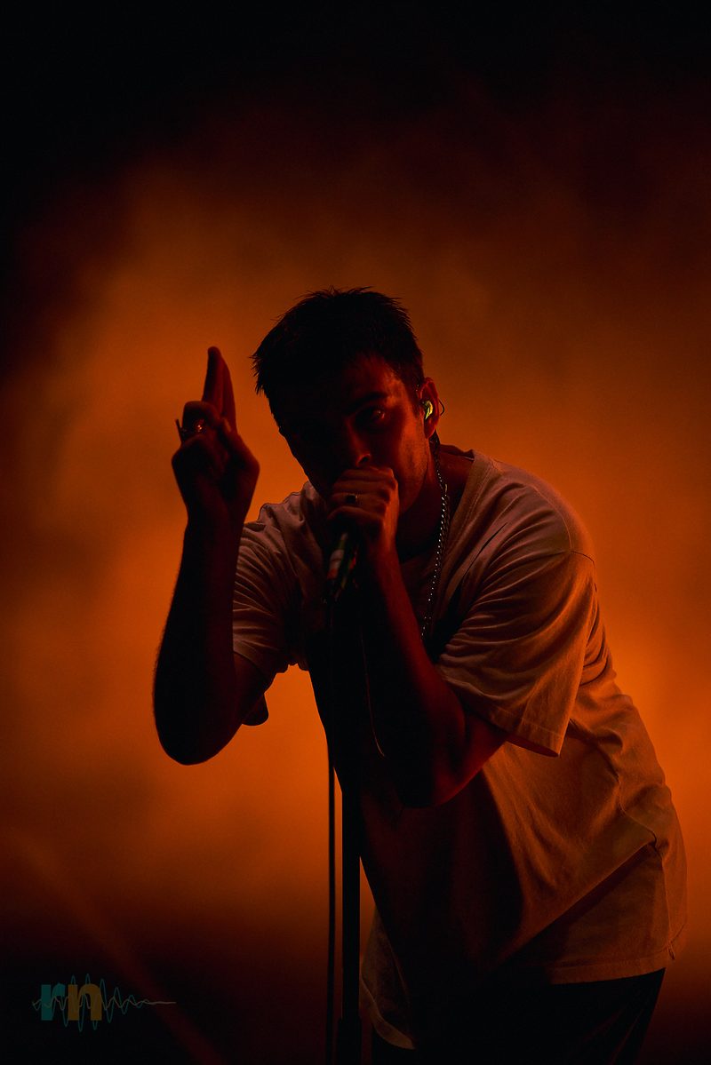 The Fontaines D.C. singer points upwards while performing under orange light in Alicante, Spain.