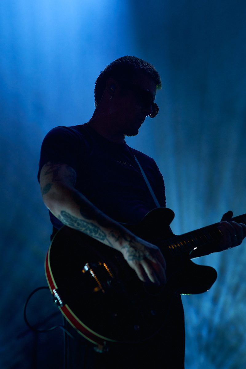 A Fontaines D.C. guitarist plays in silhouette against blue light in Alicante, Spain.