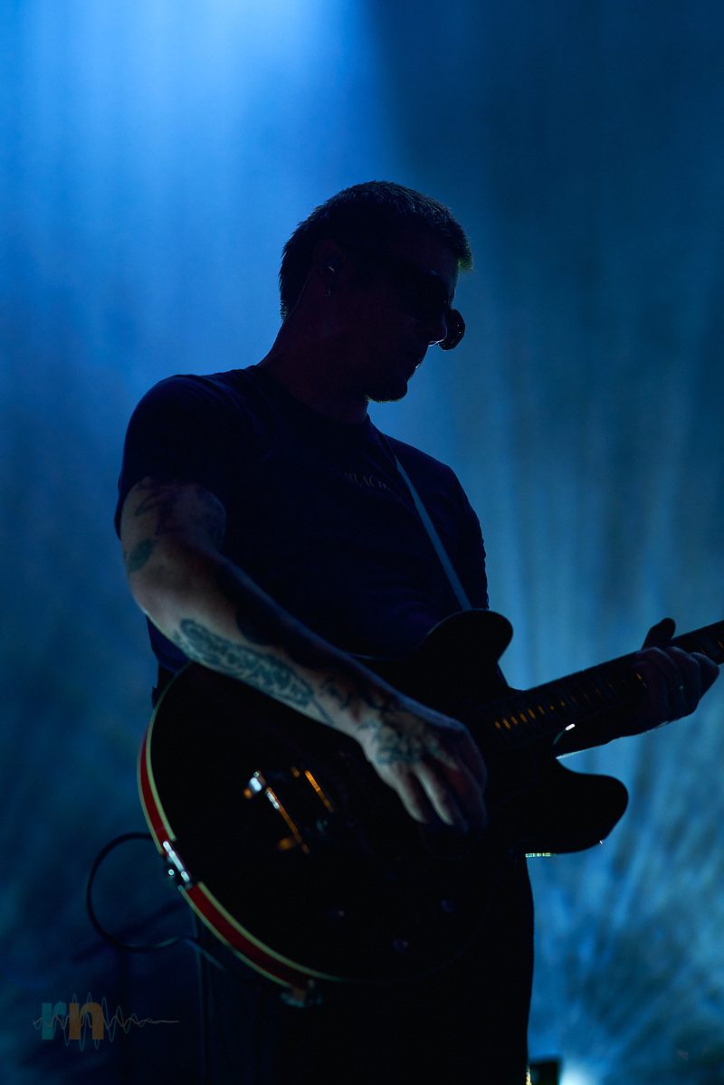 A Fontaines D.C. guitarist plays in silhouette against blue light in Alicante, Spain.