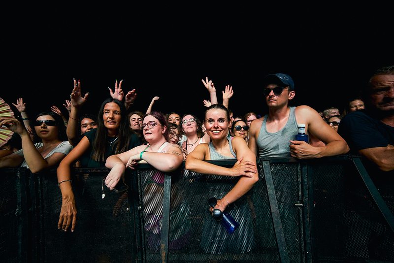 The Fontaines D.C. crowd smiles and raises their hands in the front row in Alicante, Spain.