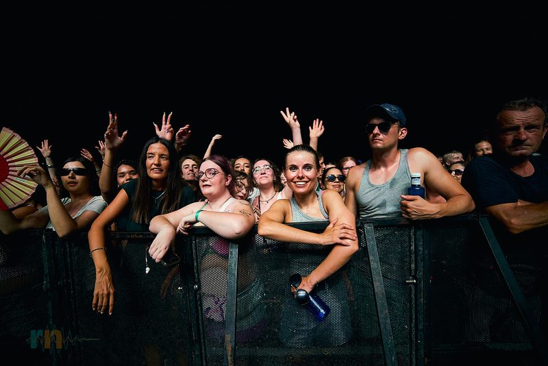 The Fontaines D.C. crowd smiles and raises their hands in the front row in Alicante, Spain.