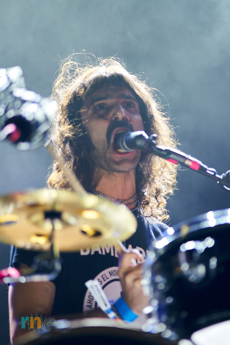 The MAQUINA. drummer sings into the microphone behind the cymbals at Canela Party 2026.