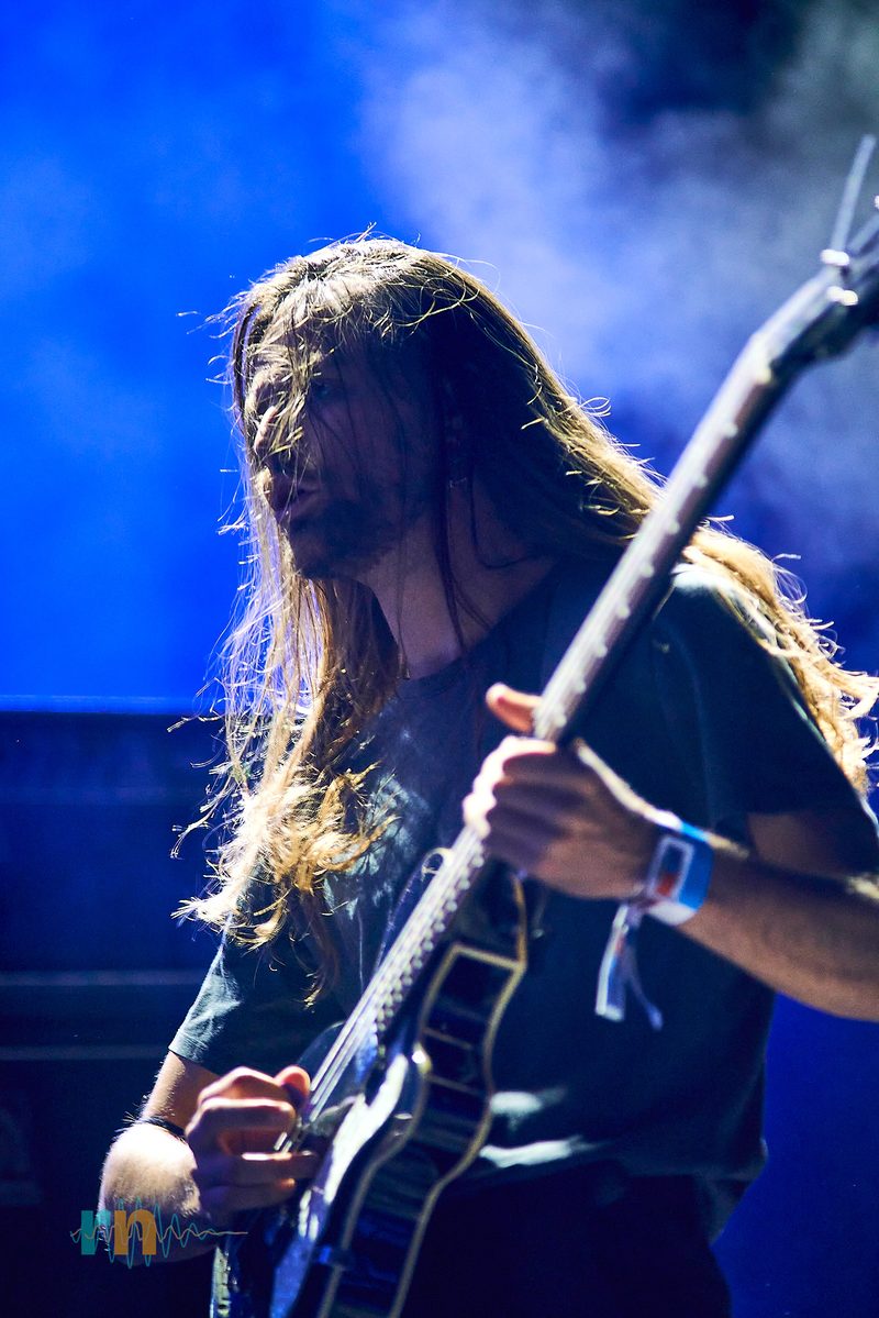 A MAQUINA. musician plays with hair covering his face beneath blue light at Canela Party 2026.